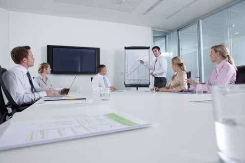 Businessman standing at chart and leading meeting in conference Businessman standing at chart and leading meeting in conference